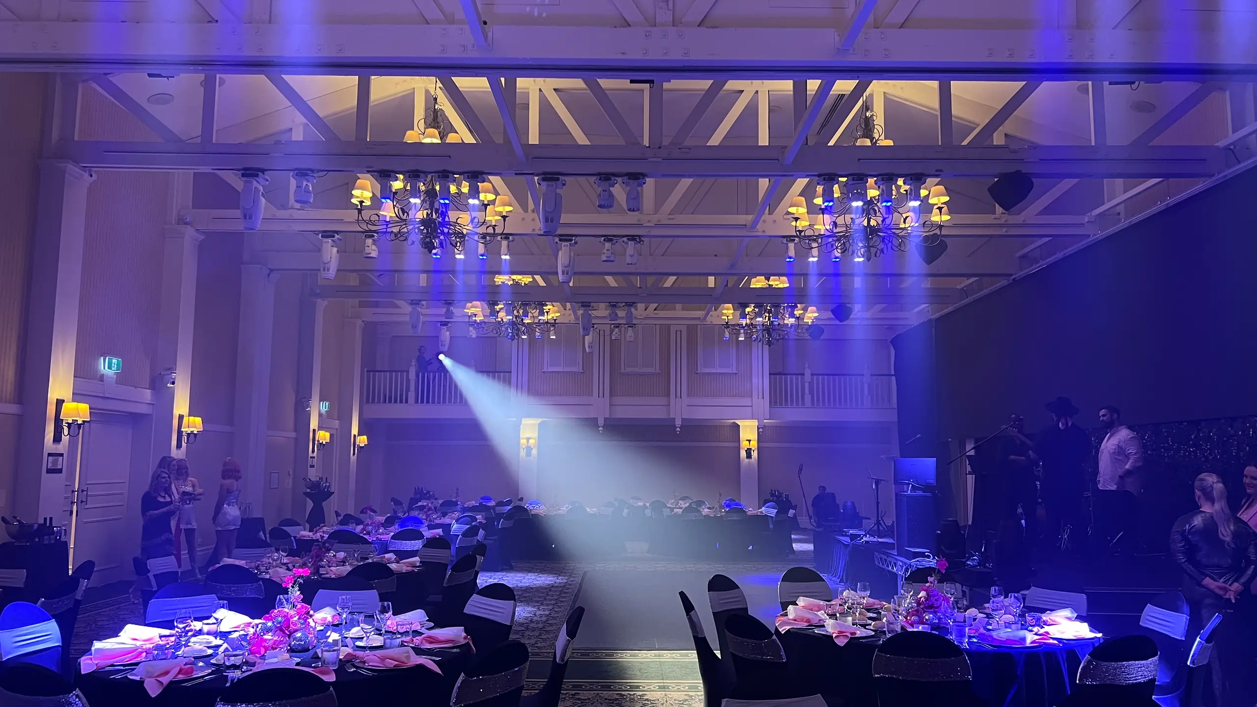 Professional LED uplighting fixtures casting colored light on venue walls for dramatic effect at corporate events.